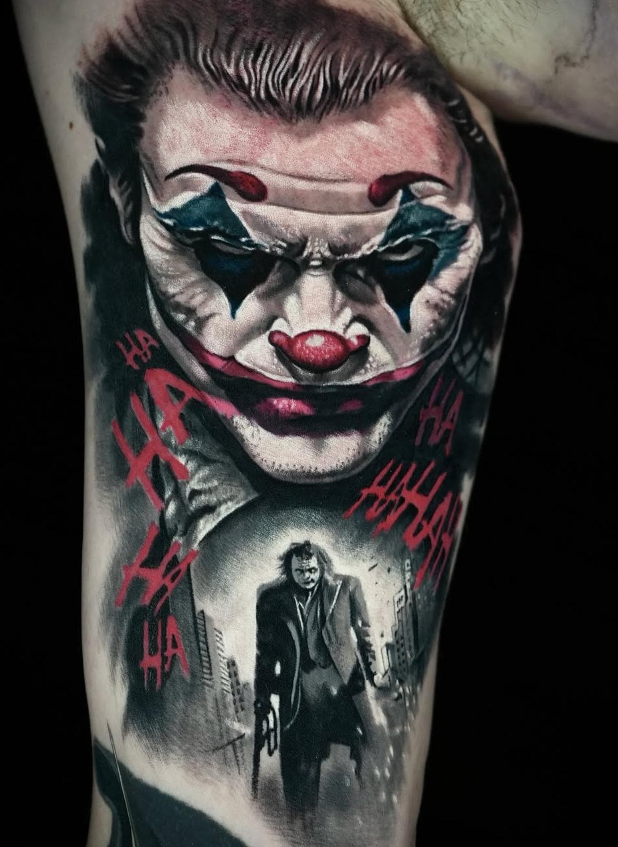 Colorful realistic clown face and scene tattoo on upper arm