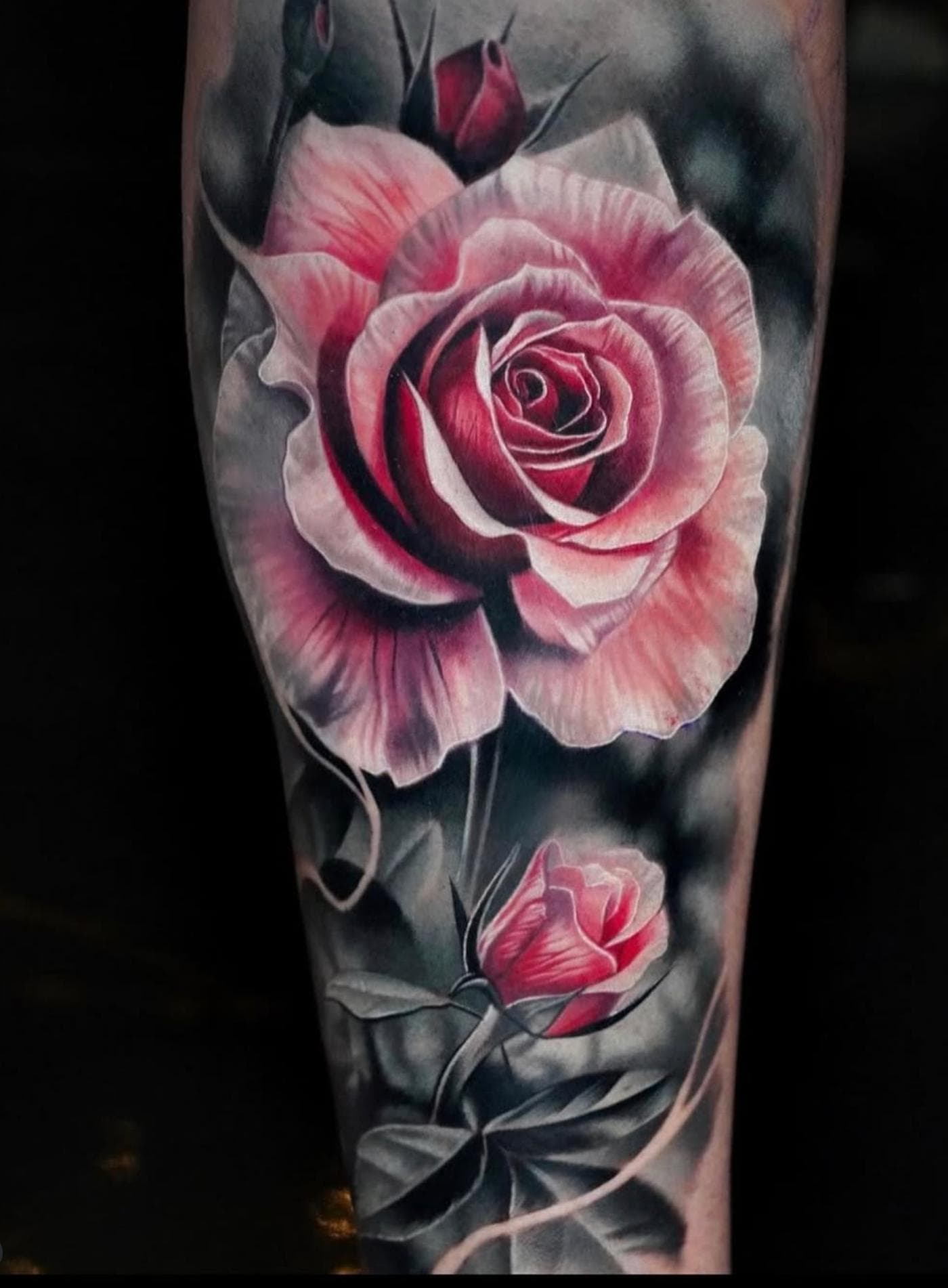 Realistic rose tattoo in black, grey, and pink on calf