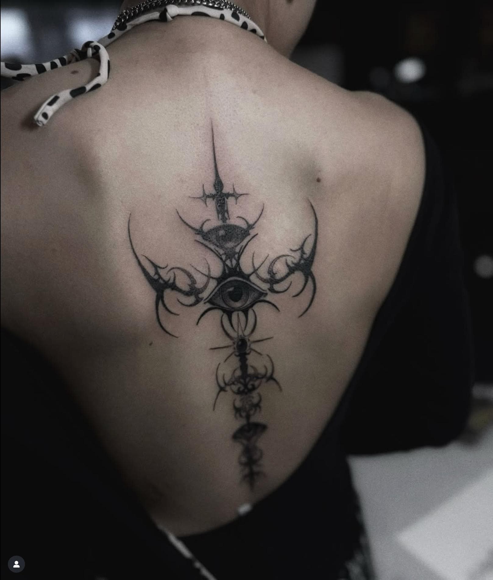 Black and grey ornamental eye tattoo on upper back