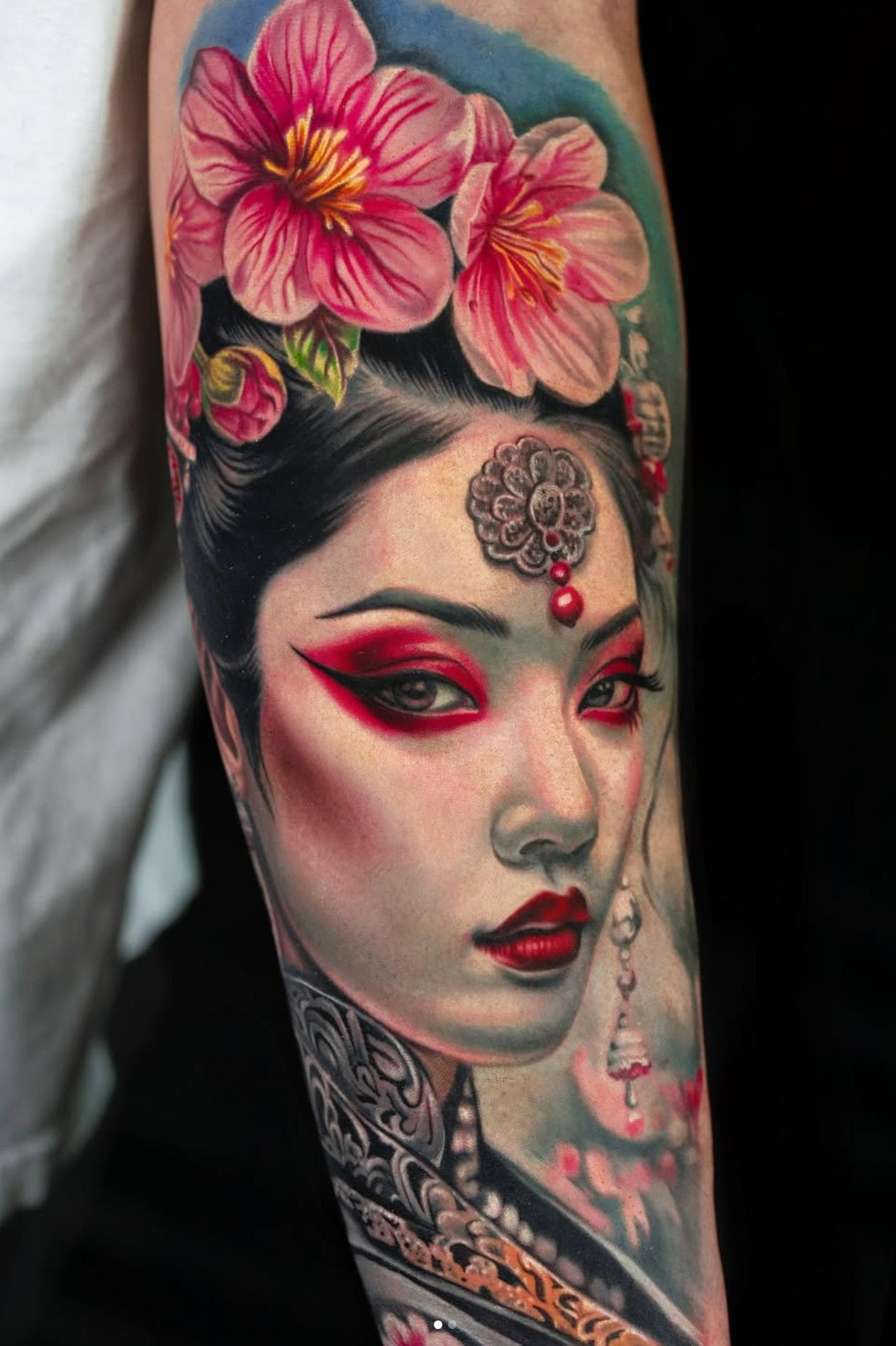 Colorful tattoo of geisha with cherry blossoms on forearm