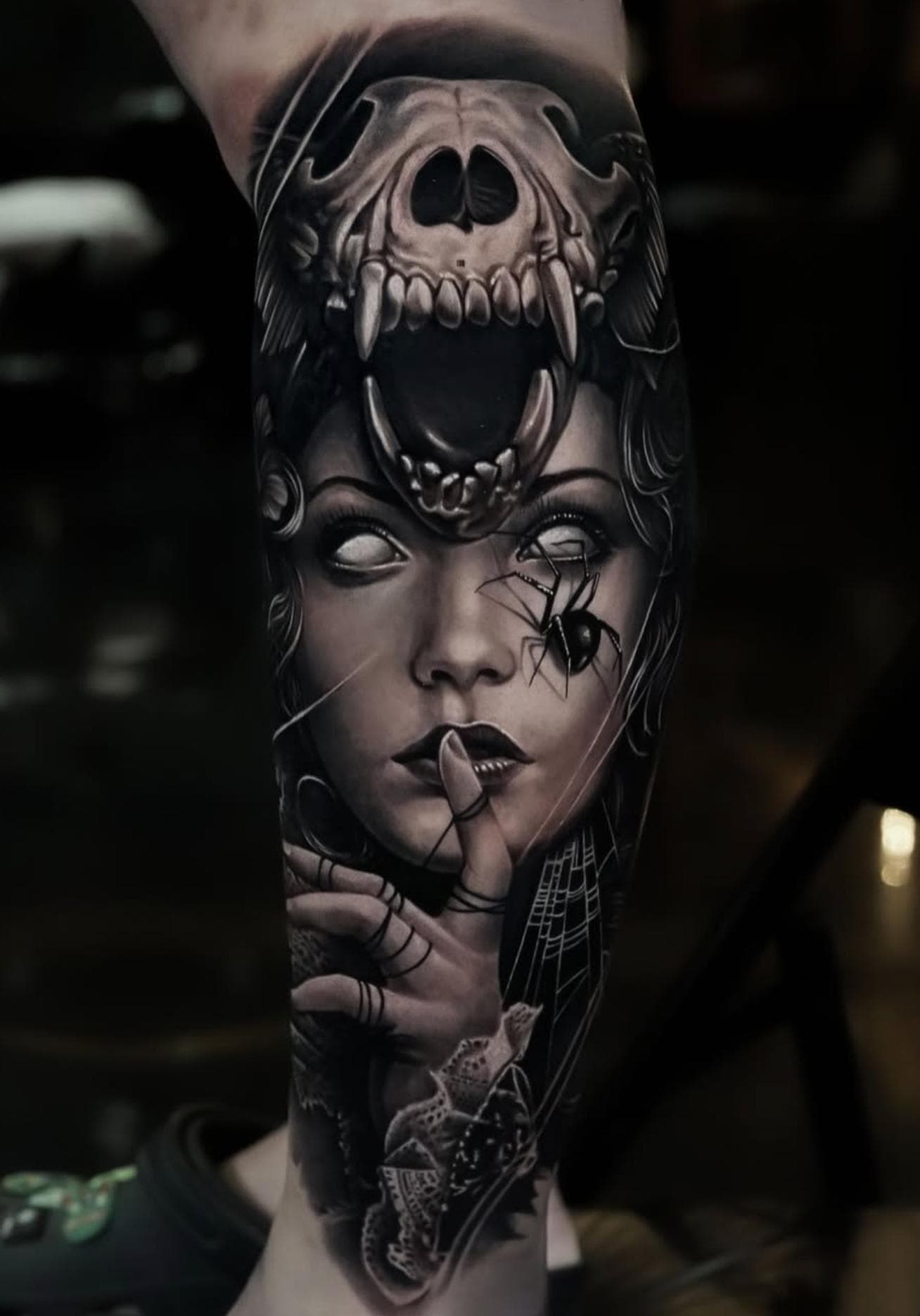 Black and grey realistic skull and spider tattoo on forearm