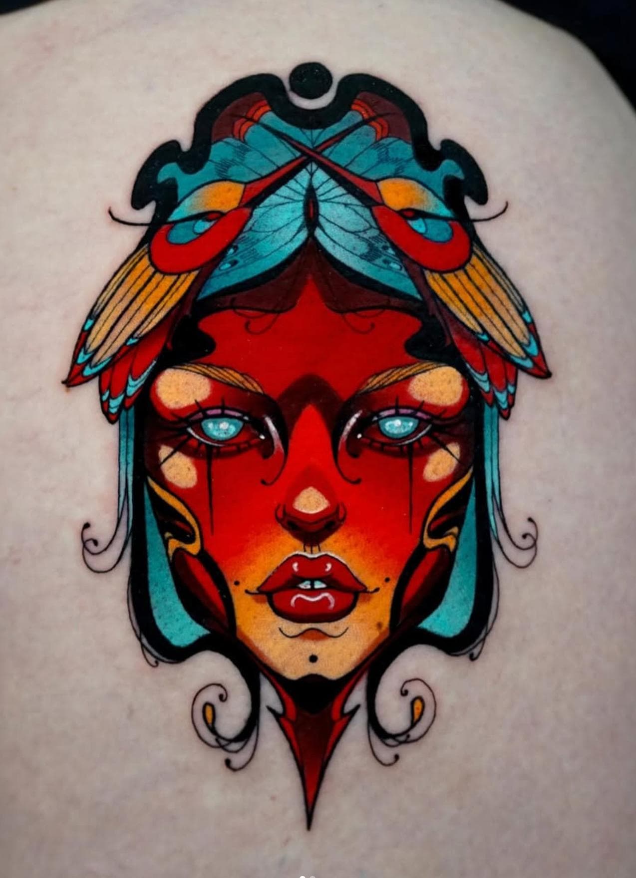 Colorful surrealistic face tattoo on upper back